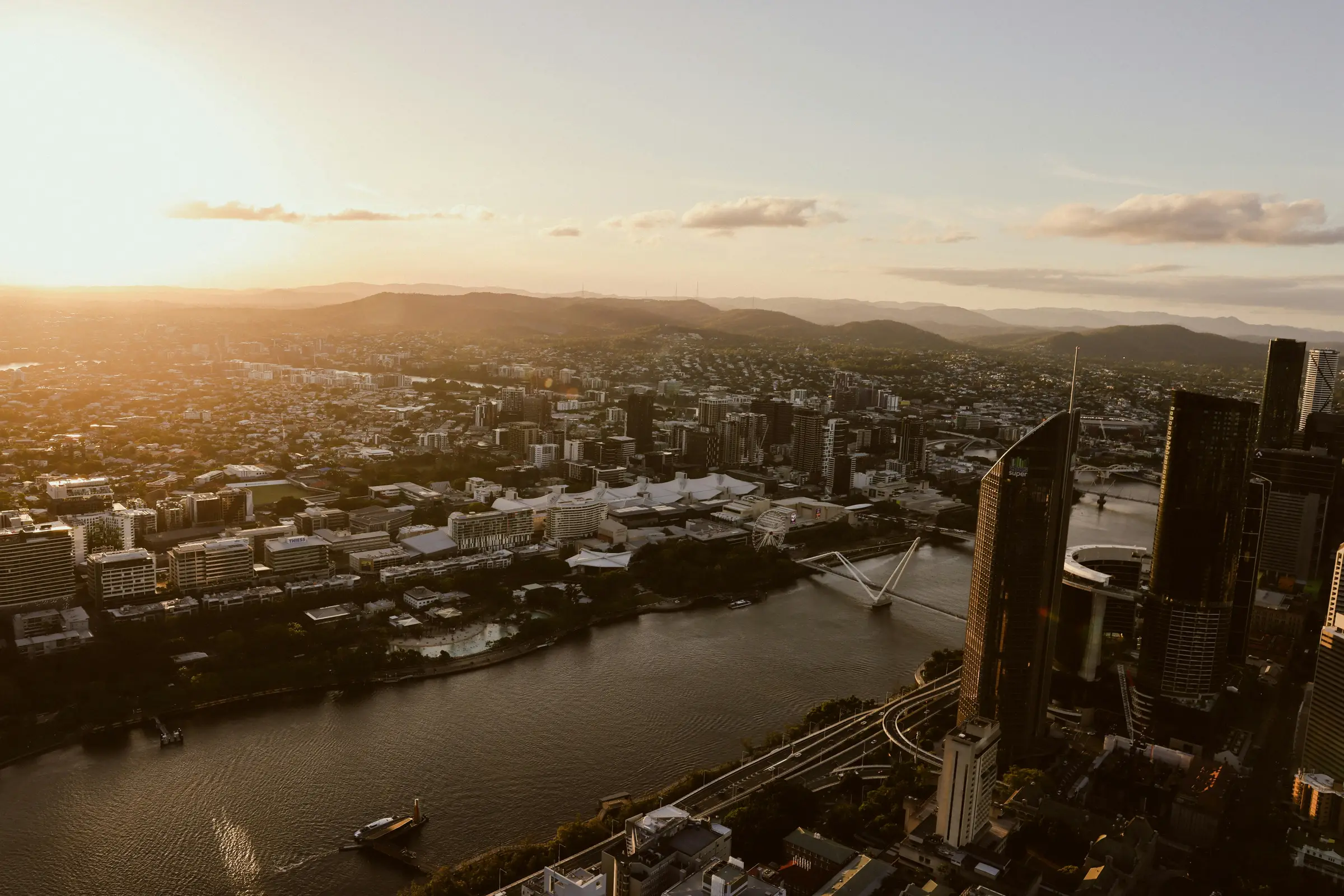 Brisbane at golden hour, looking over the river and the city towards the hills